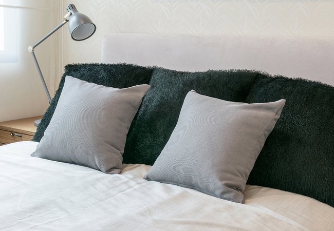 diseño de interiores de dormitorio con almohadas grises en la cama blanca